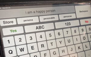 A keyboard is shown with the words typed "I am a happy person."